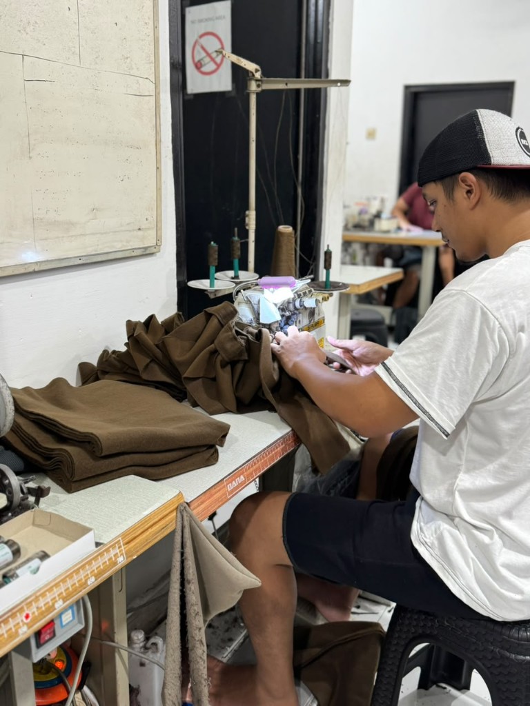 Close-up proses jahit garment untuk kontrol kualitas di mesin produksi Vertex
